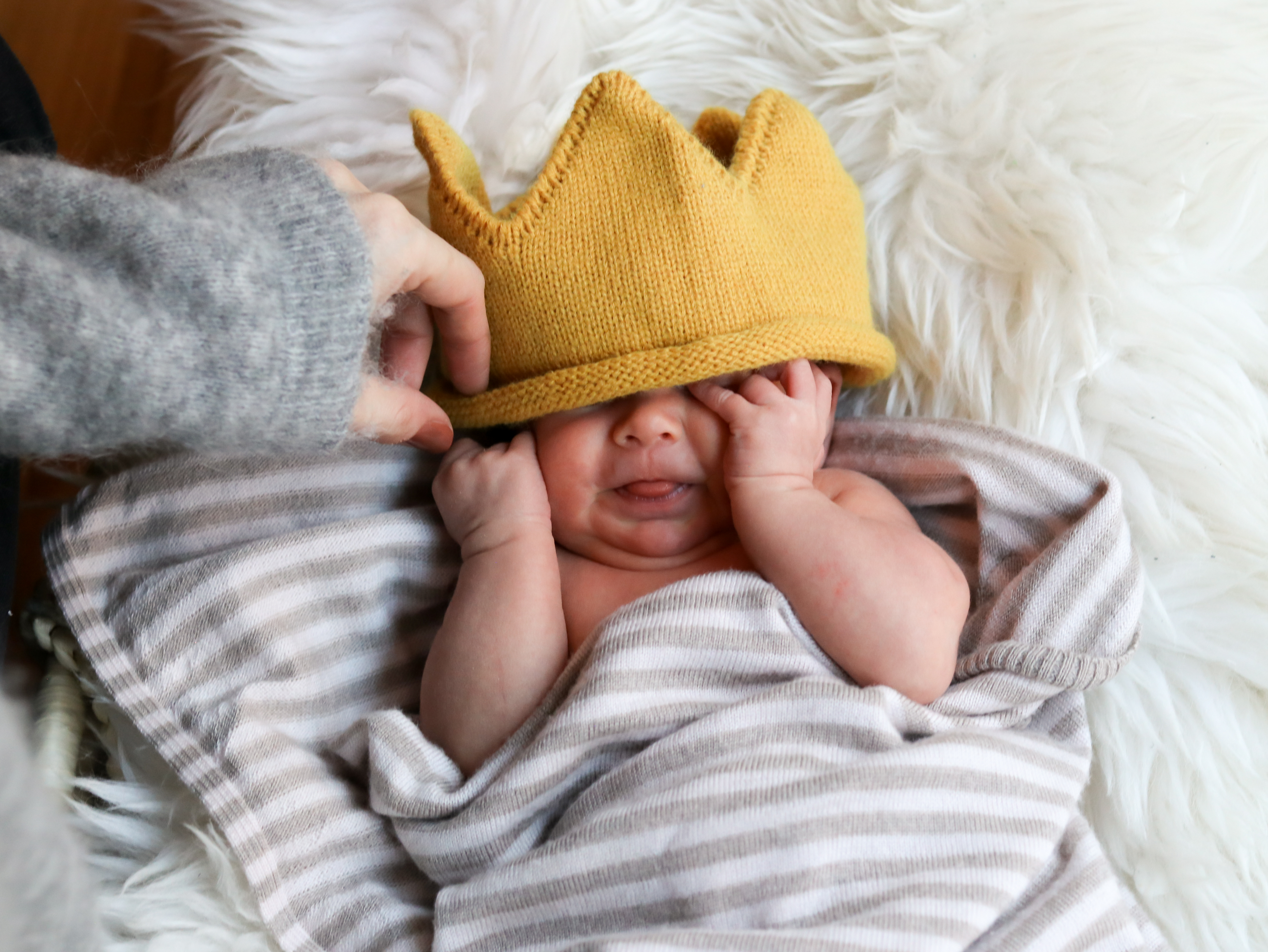 Cute newborn with crown covering face, newborn photography session