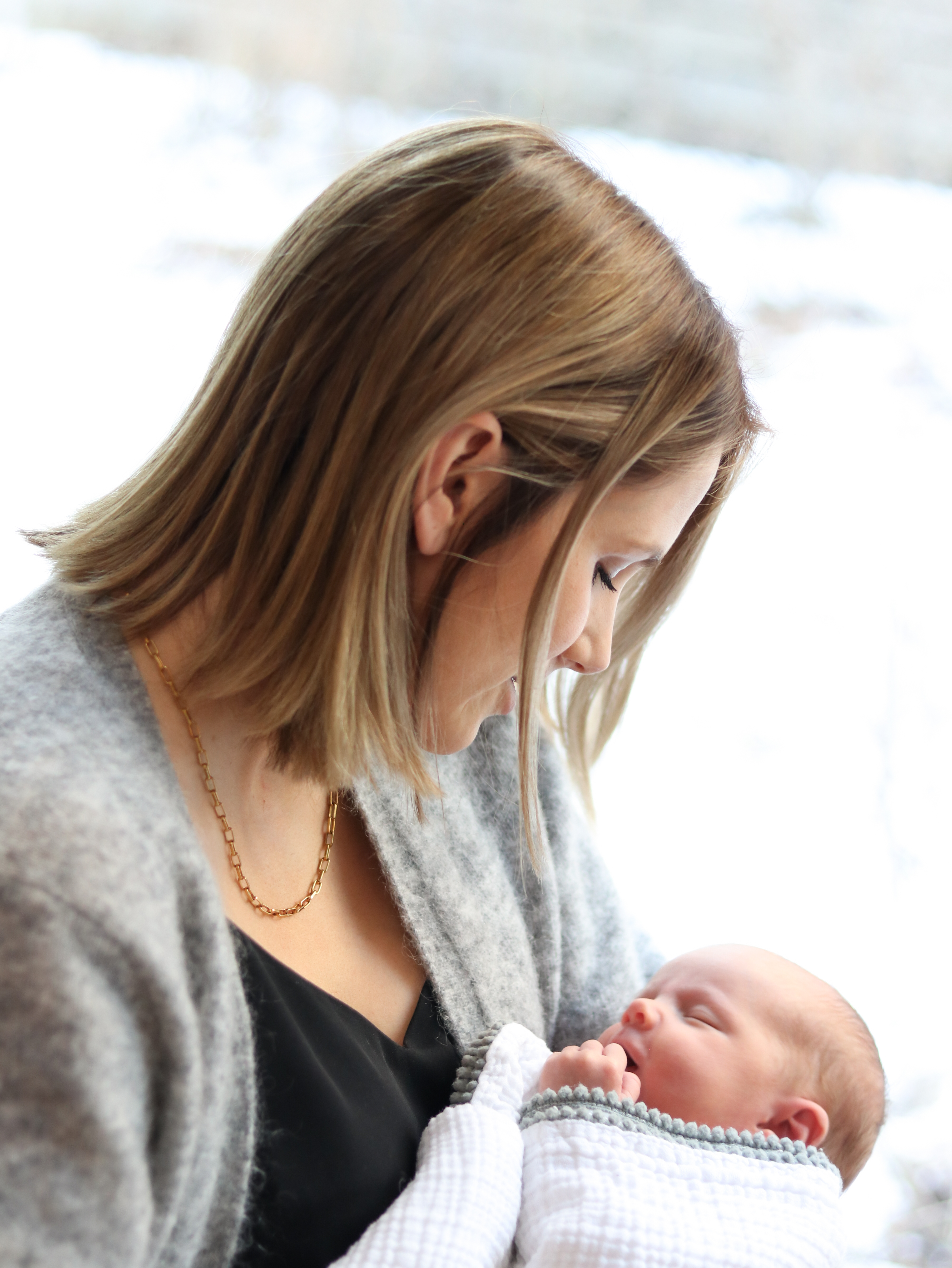 Mom smiling at wrapped baby with hair over face, newborn photographer in pagosa