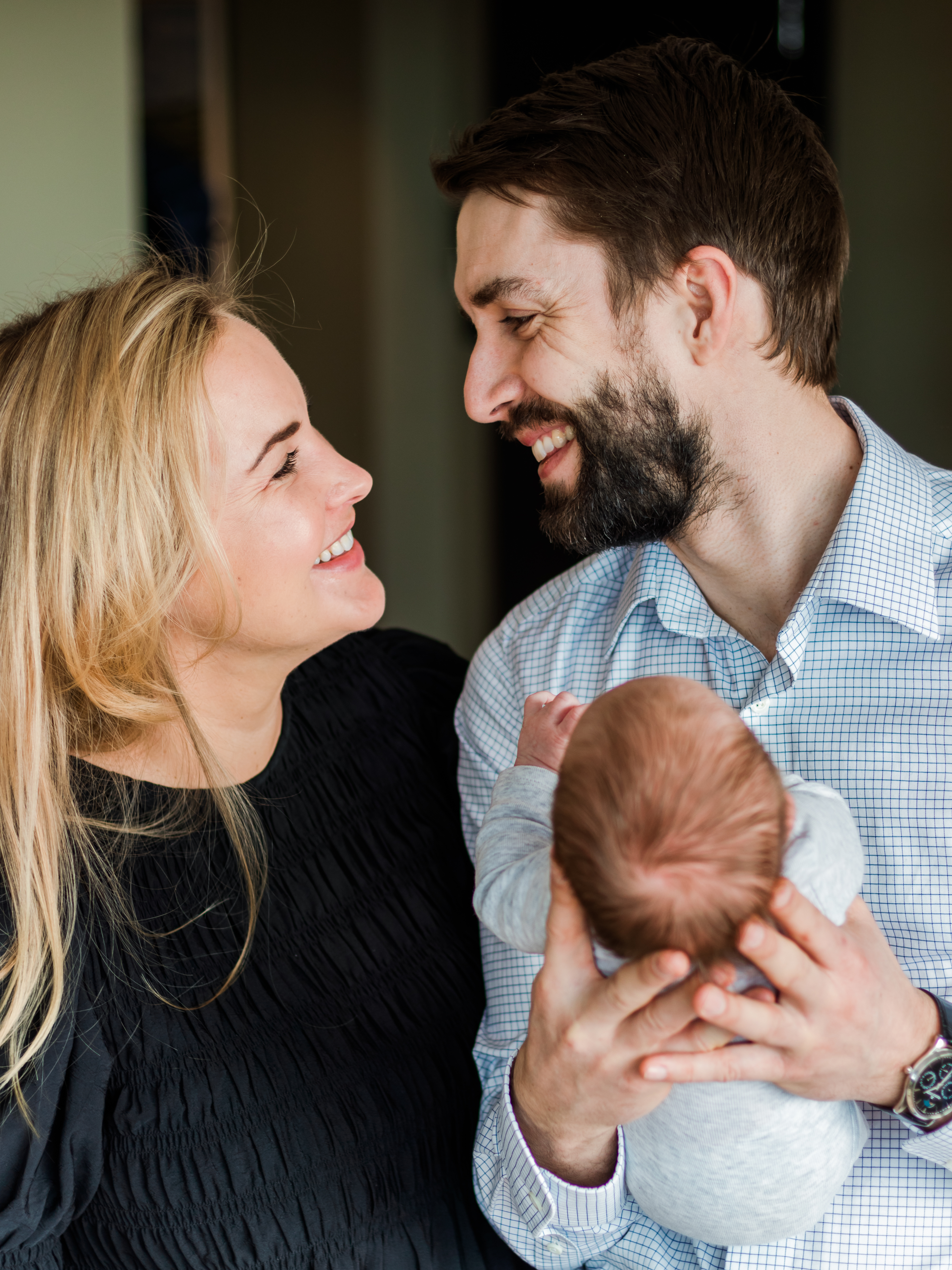 Couple smiling at each other while man holds newborn