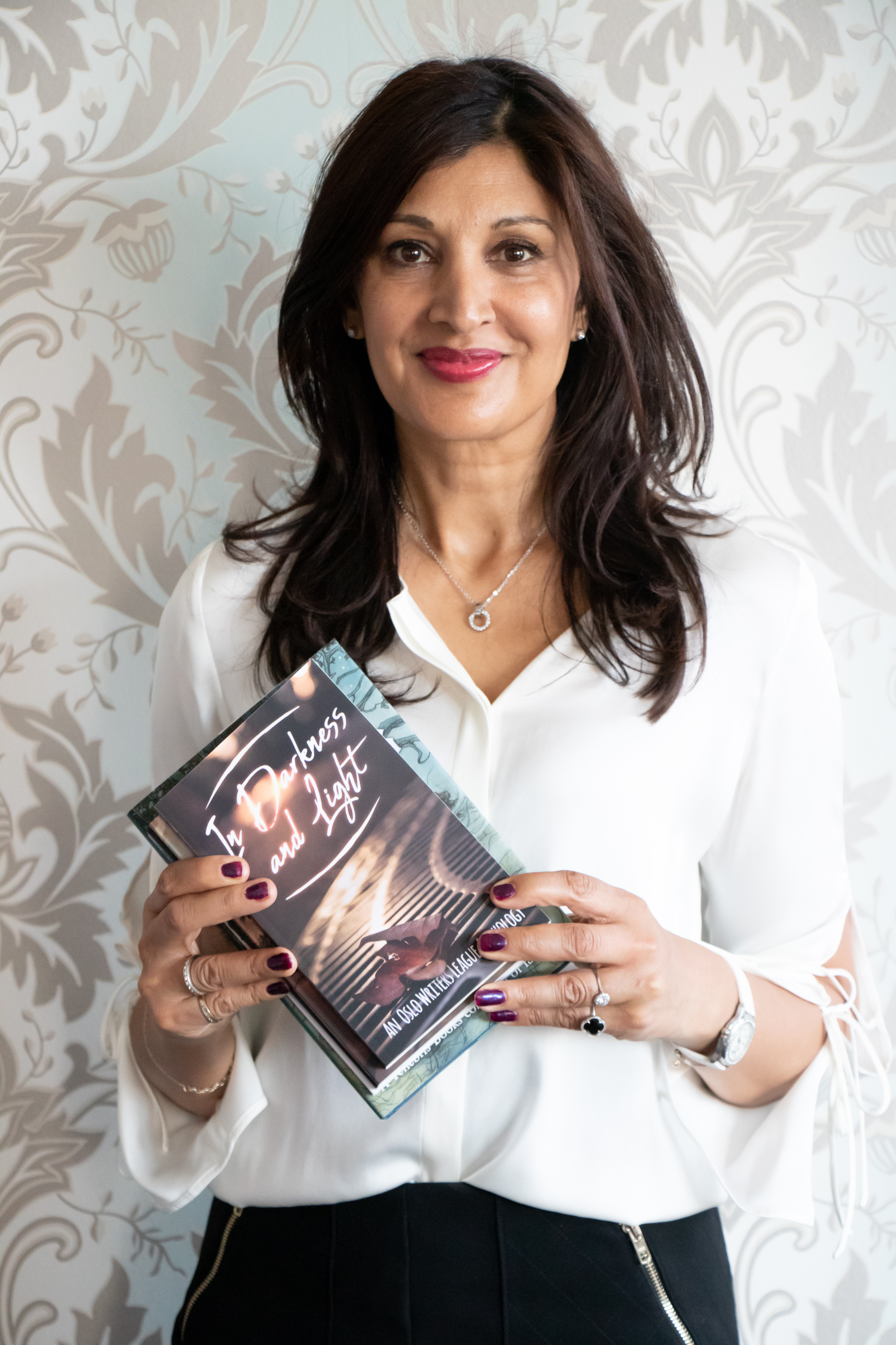 Author holding books standing in front of swirling wallpaper, branding photographer in Colorado