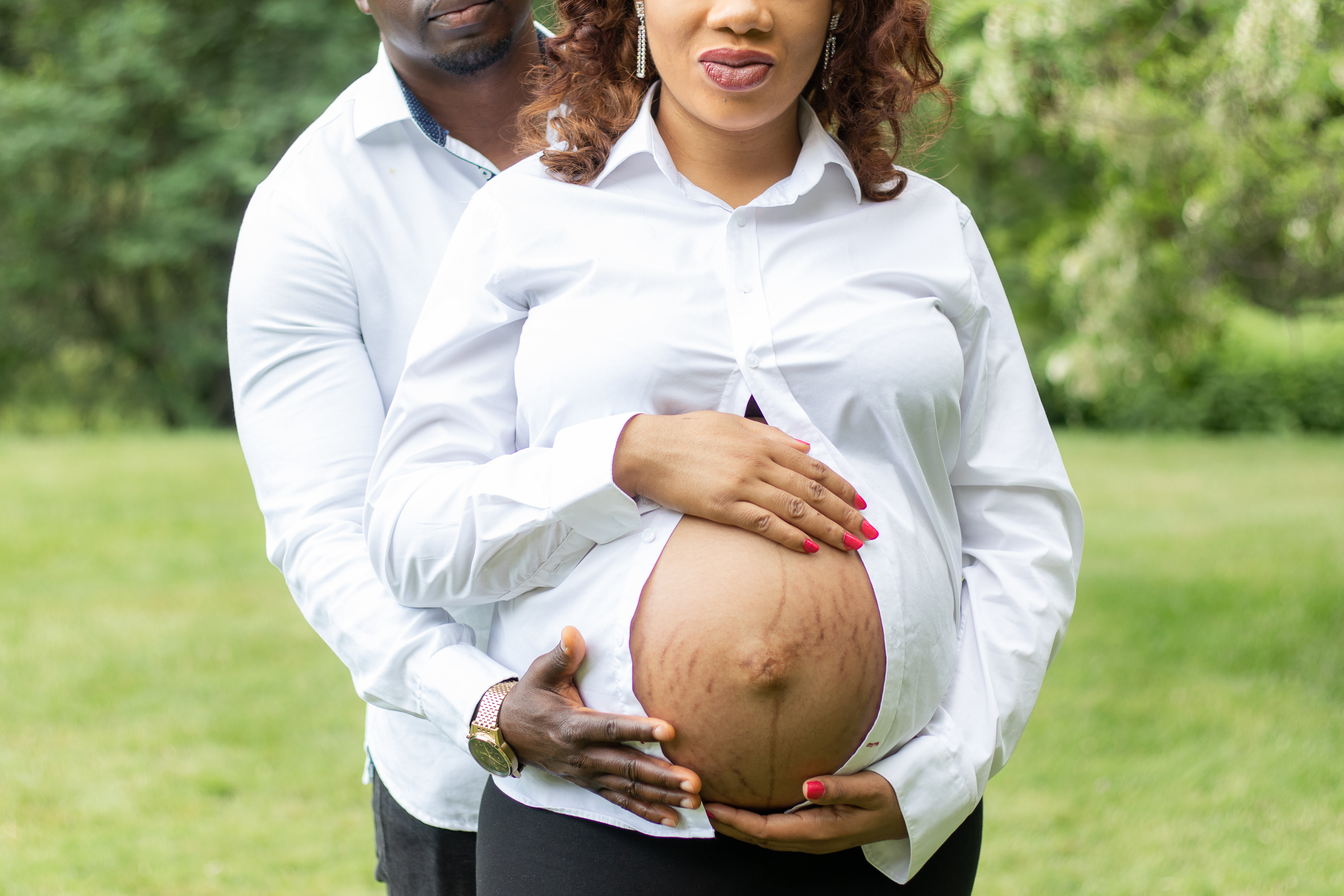 Couple holding baby bump focuses on the bump, nature photographer