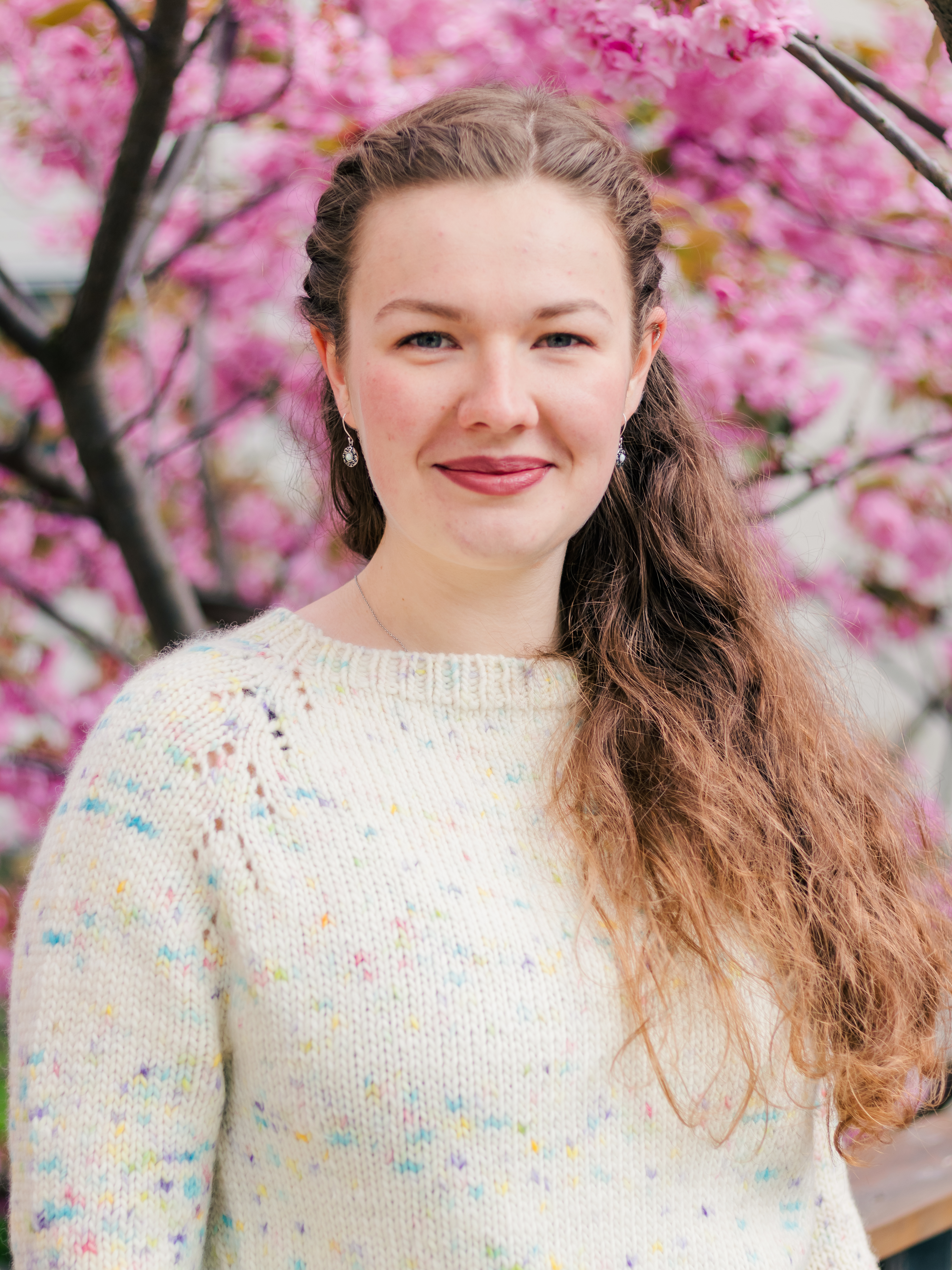 Woman in front of pink blossoming tree; branding photographer near me