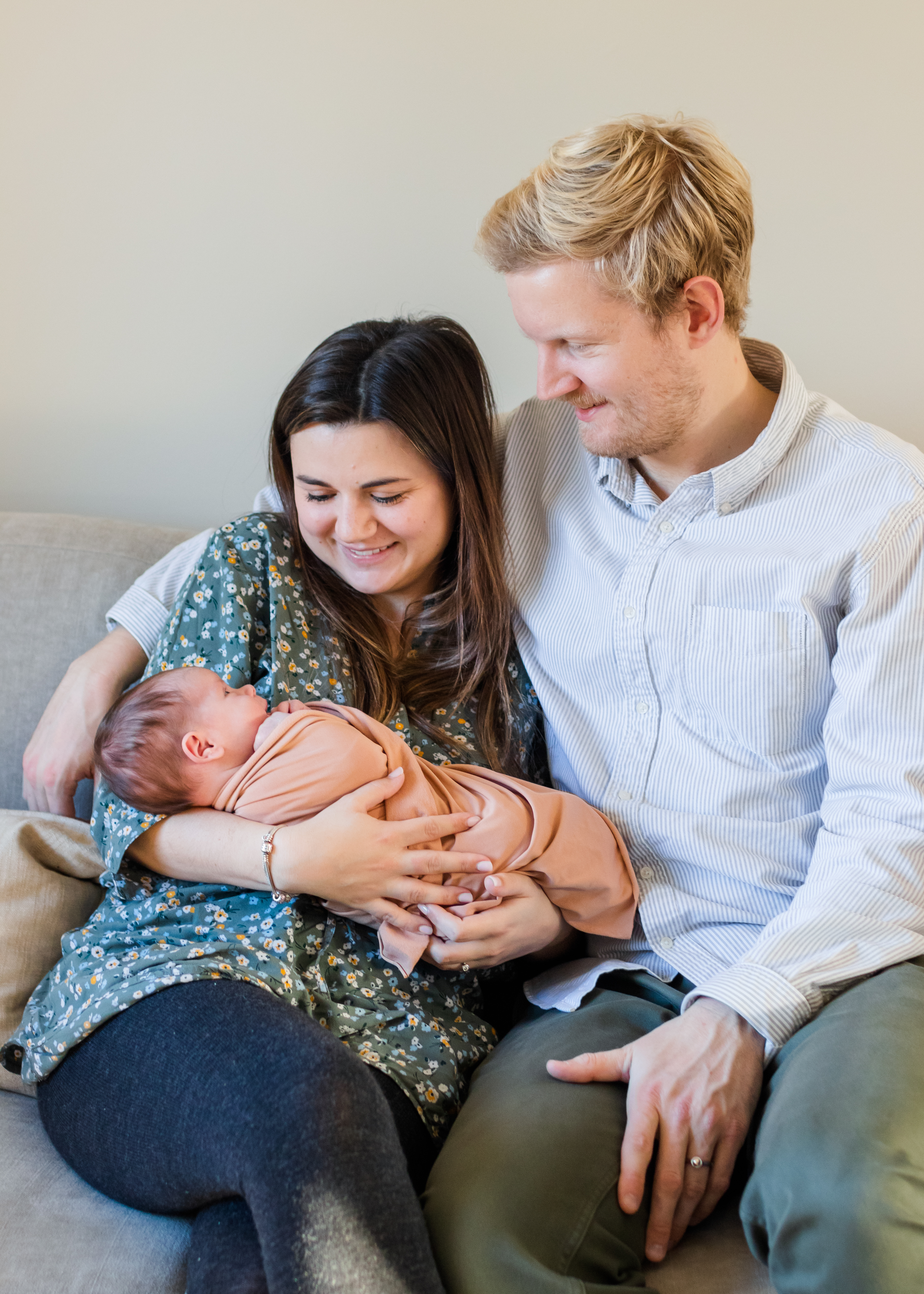 Mom and dad smiling at wrapped newborn photographer near me