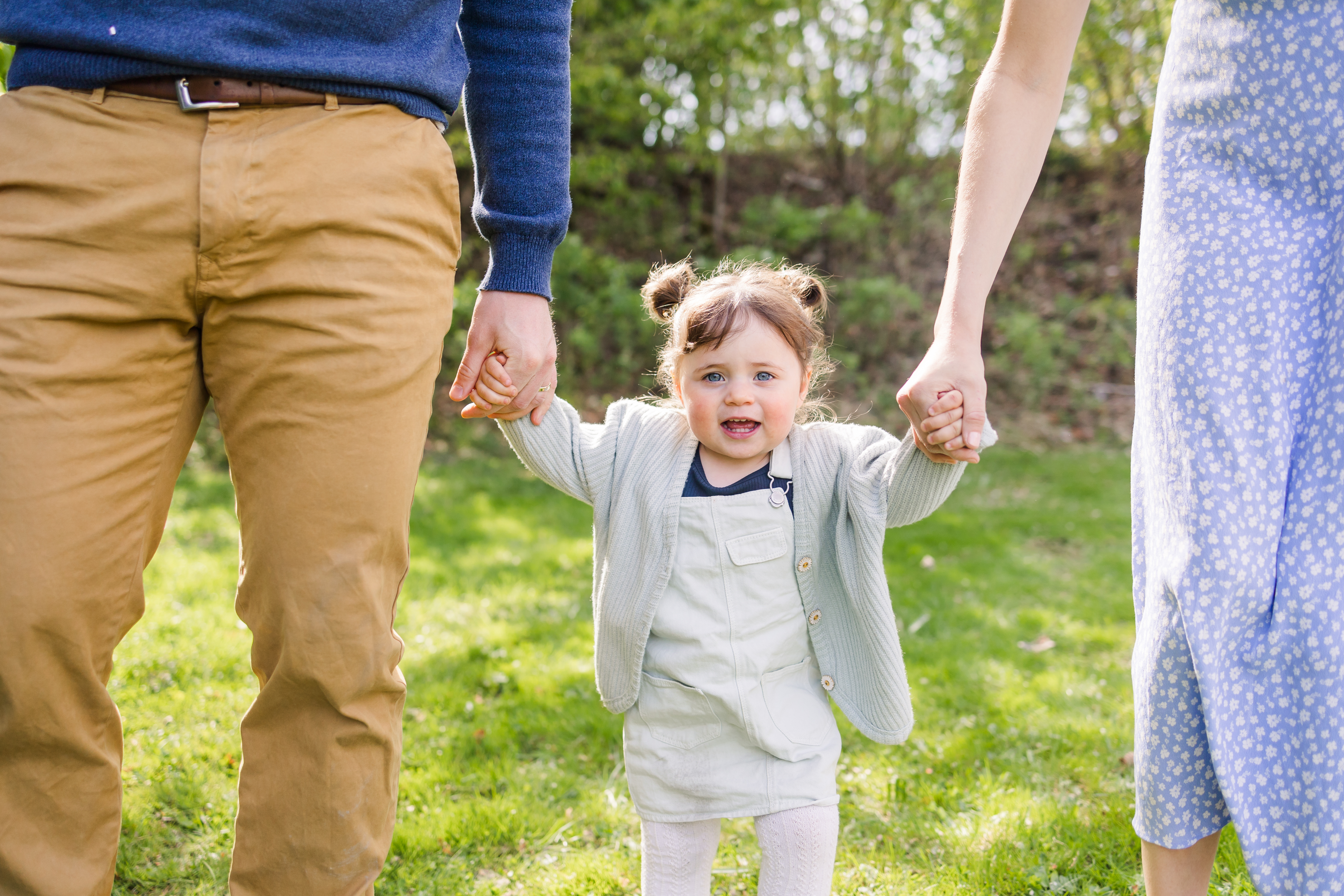 Smiling toddler holding parents hands