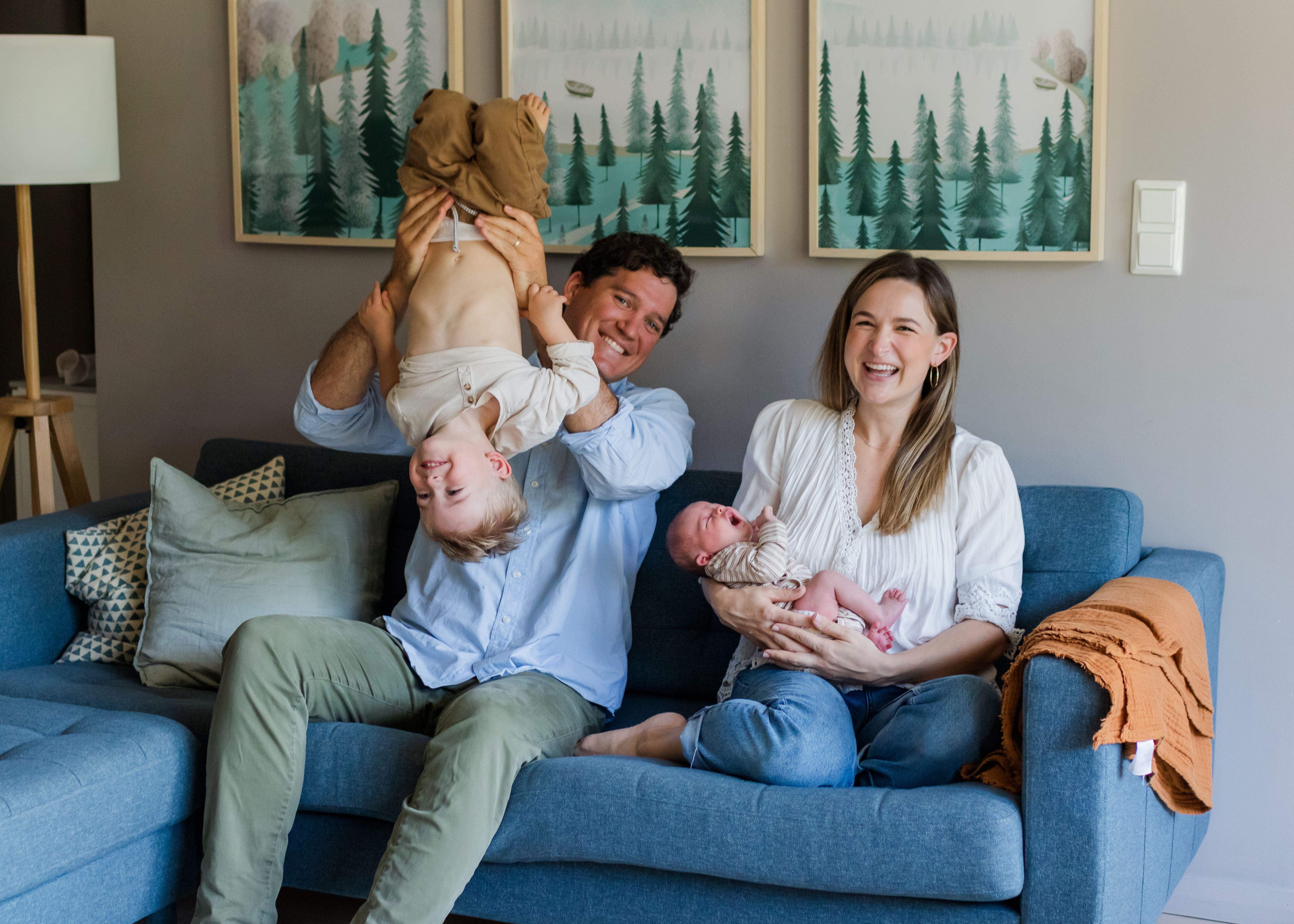 Family of four- mom holding infant, dad holding toddler upside down in their home baby photography in Colorado
