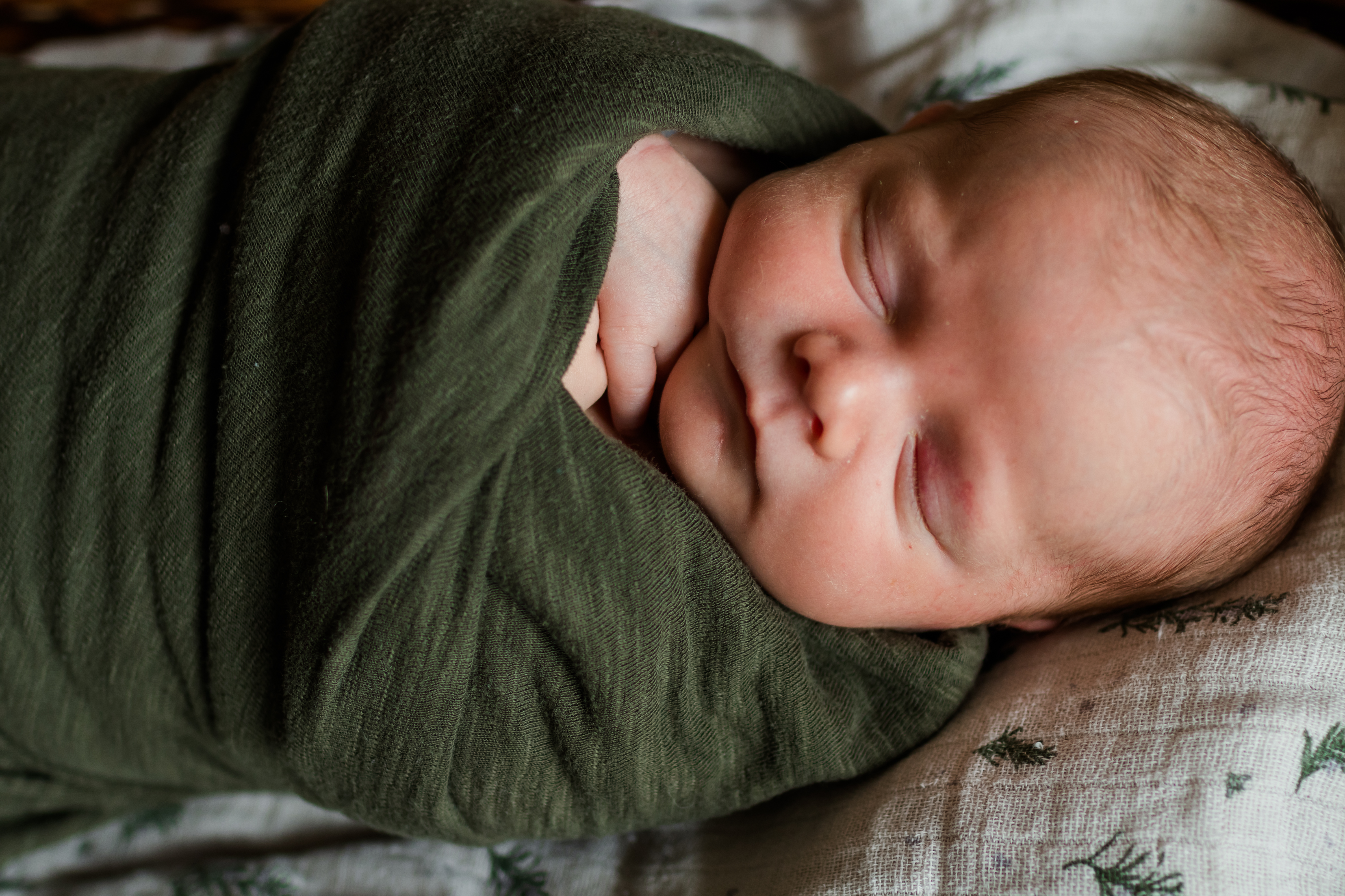 close-up of infant sleeping, swaddled in green wap. baby photographer in south fork