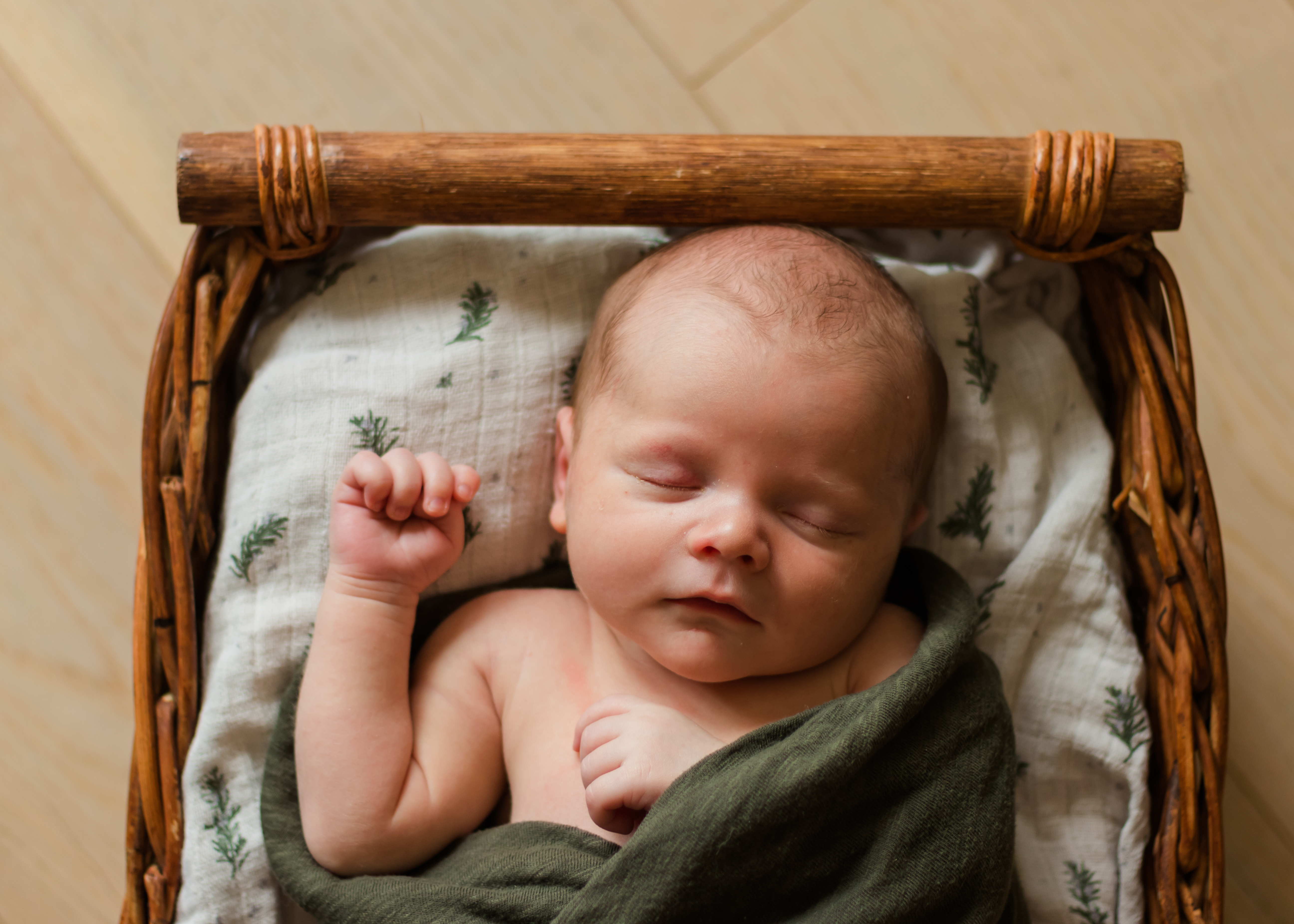 Baby in basket with eyes closed, newborn photographer in Colorado