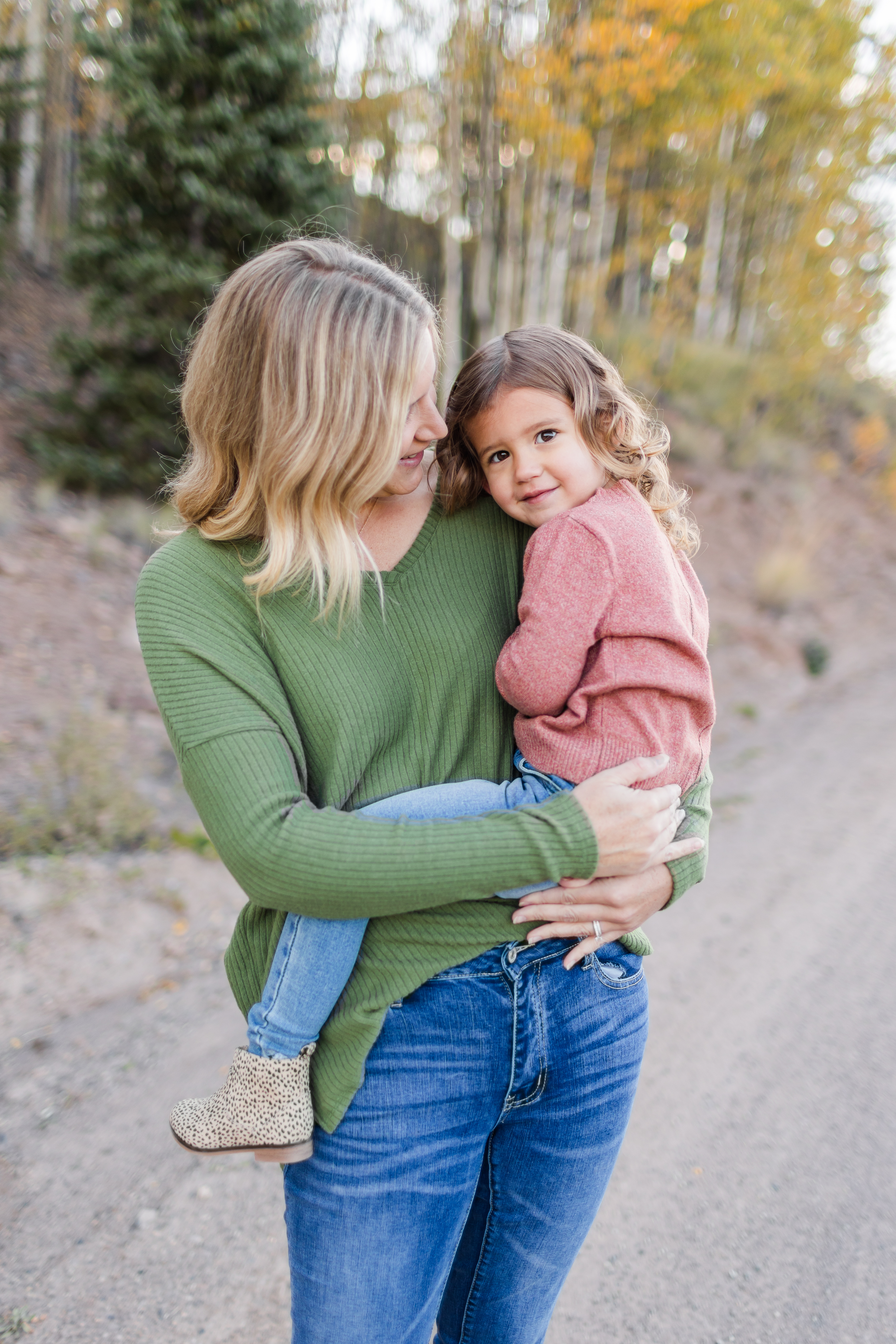 Girl snuggling with mom, looking at camera in Creede, Colorado